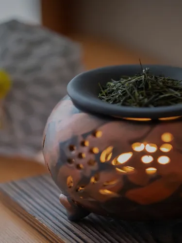陶器製の香炉に、茶葉がたっぷり盛られている。香炉の下からあたたかい光が漏れており、落ち着いた雰囲気を演出している。